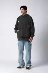 Buzo tipo canguro con capucha, de corte oversize y confeccionado en frisa rústica con efecto lavado. Presenta bolsillo frontal tipo canguro y estampado con texto en el pecho.