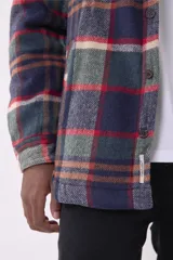 Sobrecamisa de corte holgado con diseño a cuadros en tonos beige y marrón, confeccionada en tejido de textura suave. Presenta cuello clásico, cierre frontal con botones, dos bolsillos con solapa en el pecho y puños abotonados.