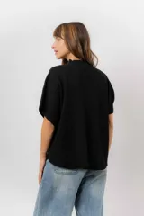 Sweater de tejido de punto color negro, con cuello semi alto y mangas cortas amplias. Presenta una silueta relajada y caída fluida.