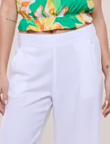 Pantalón crop de lino y rayón, con diseño wide leg de corte holgado, estampado tropical de hojas en tonos verde, azul y marrón sobre fondo blanco. Cuenta con pretina trasera elastizada y bolsillos delanteros.