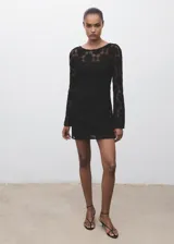 Vestido corto de crochet negro con cuello redondo, mangas largas acampanadas y espalda abierta con cierre de lazo. Incluye forro interior.