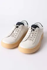 Championes urbanos de cuero blanco con suela de goma color caramelo y detalle de talón en color azul oscuro.