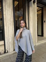 Poncho de hilo liviano en color gris, con cuello alto y diseño de caída fluida y asimétrica.