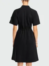 Vestido negro de algodón con cuello polo, cierre frontal con cremallera, mangas cortas, cintura ajustable con cordón y bolsillos laterales.