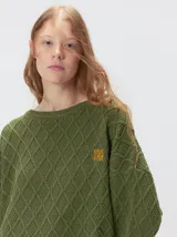 Sweater de cuello redondo con diseño de tejido en relieve de rombos, manga larga y calce holgado. Presenta logo bordado en el pecho y aberturas laterales en el ruedo.