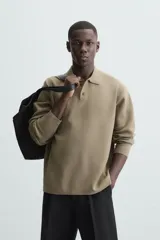Polo de punto de manga larga con cuello solapa y cierre frontal de botones. Presenta un diseño de corte regular con aberturas laterales en el bajo.