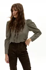 Camisa de manga larga confeccionada en popelina de algodón, con estampado geométrico en tonos verdes y negros. Presenta cuello clásico camisero, hombros ligeramente abullonados y cierre frontal con botones de nácar.