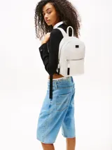 Mochila blanca de poliuretano con acabado texturizado, cierre de cremallera, asa superior, correas ajustables, bolsillo interior con cremallera, bolsillo exterior con cremallera e insignia de Tommy Jeans en la parte delantera.