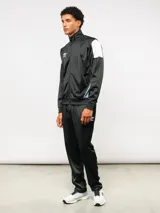 Conjunto deportivo Umbro compuesto por campera de cuello alto con cierre frontal y pantalón de corte recto. La campera presenta bloques de color blanco en los hombros y el logo de la marca bordado en el pecho. Confeccionado en tejido sintético con acabado satinado.