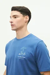 Remera de manga corta color azul, con calce regular y cuello redondo. Presenta un diseño bordado en el pecho con motivos playeros y la frase 'sunshine time' junto al logo de la marca Brooksfield.