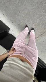Pantalón de tiro medio confeccionado en tela jersey rib color rosa, con diseño de pierna ancha y bolsillos laterales. Presenta costuras visibles en hilo de color contrastante.