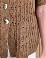 Cardigan de punto color tostado, de manga corta y cuello redondo, con cierre frontal de botones y diseño texturizado.