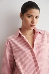 Camisa de corte oversized con estampado de rayas verticales, cuello clásico, cierre frontal con botones y bolsillo en el pecho.