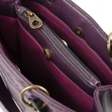 Cartera de mano color púrpura, con diseño acolchado en símil cuero soft y costuras a tono. Tiene acceso con cierre y broches imantados, herrajes dorados y correa regulable para usar como bandolera. El interior está forrado en tela de algodón y poliéster, con un bolsillo con cierre y dos abiertos.
