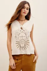 Musculosa de viscosa color blanco, sin mangas, con escote en V decorado con apliques y un gran estampado frontal de temática astrológica en tonos dorados y oscuros.