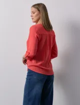 Blusa blanca de gasa marca Zac & Rachel, con cuello a la base, escote en V, abertura central con botones, bolsillo aplicado en el pecho y mangas largas regulables con presilla y botón. Tiene terminación opcional de nudo en el ruedo.