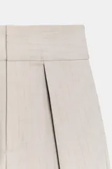 Pantalón de tiro alto con diseño tipo balloon, confeccionado en tejido con viscosa. Presenta pliegues frontales, bolsillos laterales ocultos y cierre frontal con cremallera, botón interior y ganchos metálicos.