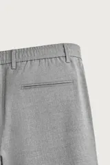 Pantalón de corte slim fit y color negro, confeccionado en tejido elástico. Cuenta con cintura elástica, trabillas, bolsillos frontales y cierre con cremallera y botón.