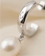 Caravanas colgantes de plata 925, compuestas por un aro pequeño con incrustaciones de circonia y una perla natural en forma de gota.