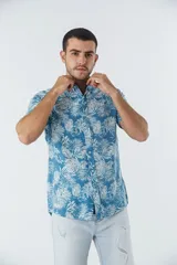 Camisa de manga corta con estampado botánico de hojas en tonos azul y blanco. Presenta cuello clásico, cierre frontal abotonado y corte slim.