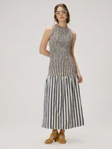 Vestido midi de silueta en A, sin mangas y con escote redondo, confeccionado en algodón. Presenta un diseño de rayas verticales combinadas en color crudo y azul marino, con cuerpo ajustado mediante frunces elásticos y falda amplia con rayas más anchas.
