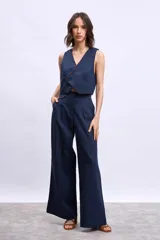 Chaleco corto azul marino con escote en V, cierre cruzado de botones y vivos en color naranja.