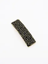Broche para el pelo rectangular con diseño de textura granulada en color negro y dorado.