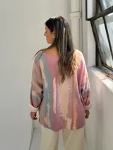 Sweater de punto con diseño abstracto en tonos rosados, beige y azul, de corte holgado, cuello en V y mangas largas con puños vueltos.