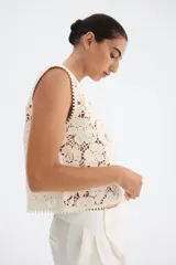 Chaleco sin mangas de punto crochet color crema, con diseño floral calado y ribetes de picot en cuello, sisas y ruedo. Cierre frontal con botones nacarados.