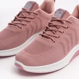 Zapatillas deportivas de mujer color rosa con capellada de malla, cordones y suela blanca.
