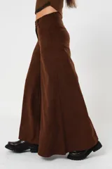 Pantalón marrón acampanado de tiro medio, con bolsillos delanteros y traseros. Cierre frontal con cremallera y botón.