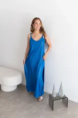 Vestido largo rojo brillante, con escote en V y tirantes finos. Presenta un corte holgado y abertura lateral en la falda.