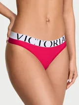 Tanga de microfibra fucsia de tiro bajo, con cintura elástica ancha en color blanco con el logotipo de la marca impreso en negro.