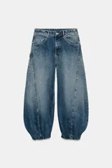 Jeans de tiro medio confeccionados en denim azul con efecto deslavado, corte holgado con diseño de volumen abullonado en las piernas y bajo con puño elástico. Cuentan con trabillas, bolsillos delanteros y traseros, y costuras decorativas marcadas.