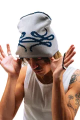 Gorro de lana tejido reversible, un lado azul marino y el otro gris, con diseño de moños en ambos lados.