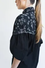 Camisa negra de manga larga con canesú estampado con diseño floral, cuello camisero y cierre frontal con botones.