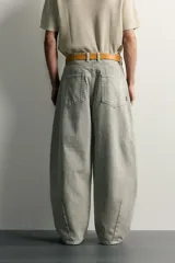 Pantalón barrel fit de mezclilla color verde militar, con efecto lavado, cinco bolsillos, cierre frontal con cremallera y botón, y detalle de pinzas en las rodillas.