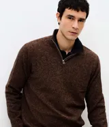 Suéter de punto con textura melange, cuello alto con cierre frontal parcial y mangas largas. Presenta un diseño estructurado y corte regular.