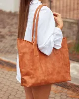 Bolso tipo shopper de cuero, color marrón tostado, con detalle de costura artesanal en el borde superior y correas largas para llevar al hombro.