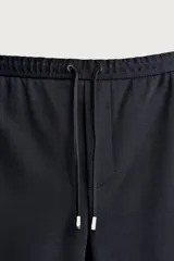 Bermuda regular fit de tejido elástico color blanco, con cintura elástica ajustable mediante cordón, bolsillos delanteros y bolsillos traseros de vivo.