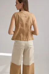 Pantalon de lino de corte recto y holgado, con diseño bicolor que combina tonos crudo y beige. Presenta bolsillos laterales y una silueta fluida.