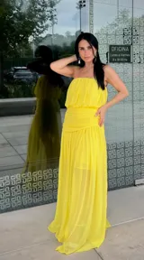 Vestido largo amarillo de estilo strapless, con cuerpo drapeado y falda fluida con tajo lateral.