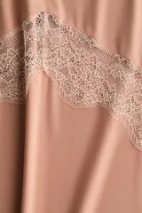 Vestido midi sin mangas de punto suave, con escote redondo y bajo asimétrico. Presenta detalles de encaje en las sisas, en la parte frontal y en el ruedo.