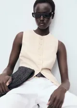 Chaleco de corte recto y diseño sin mangas, con cuello redondo y tirantes anchos. Presenta un cierre frontal con botones y forro interior de algodón.