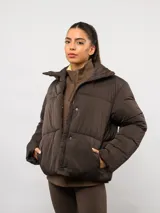 Campera puffer corta Umbro de color negro, con cuello alto, cierre frontal y bolsillos laterales. Presenta un diseño acolchado y logo de la marca bordado en el pecho.