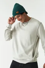 Buzo de felpa color gris claro, con cuello redondo, mangas largas y costuras a contratono. Presenta lettering estampado en el pecho, bolsillos laterales y logo en grifa de goma.