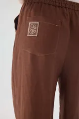 Pantalón de lino color beige, de silueta relajada, tiro medio-alto, cintura elastizada con cordón ajustable, bolsillos laterales y bolsillos traseros.