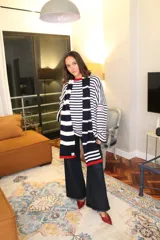 Sweater oversize de punto con diseño a rayas horizontales en color verde y blanco, cuello redondo en contraste rojo y detalle de etiqueta bordada en la manga.