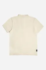 Polo de manga corta color crema con textura acanalada, cuello estructurado y logo de la marca aplicado en el frente.