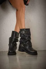 Botas de caña media color negro, confeccionadas en cuero vegano, con hebillas metálicas y suela track.